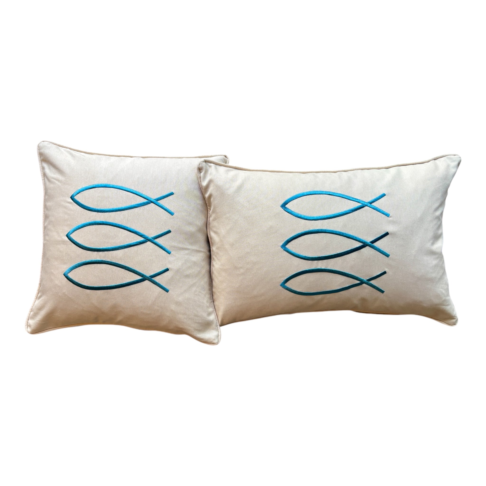 Trifin decorative pillow in sand color, measuring 17.7 by 17.7 inches, featuring three overlapping teal fish-shaped embroidery designs on a square beige fabric.
