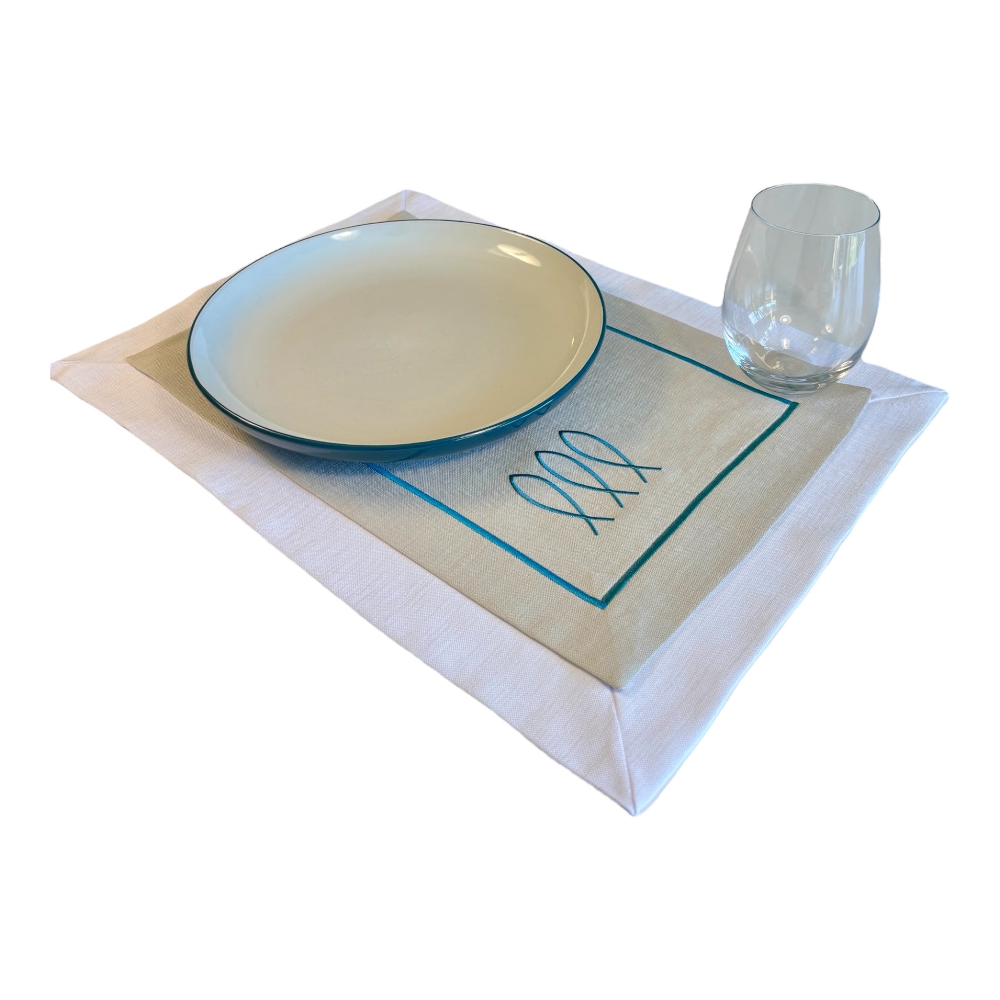 14x20 Inches35x50 Centimeters Trifin nautical table mat in Sand color, featuring three embroidered fish motifs on Sand color fabric with a white border. Designed for life at sea, it offers a balance of coastal sophistication and everyday practicality for onboard dining experiences.